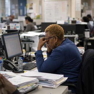 An overloaded staff member at her desk in a busy office